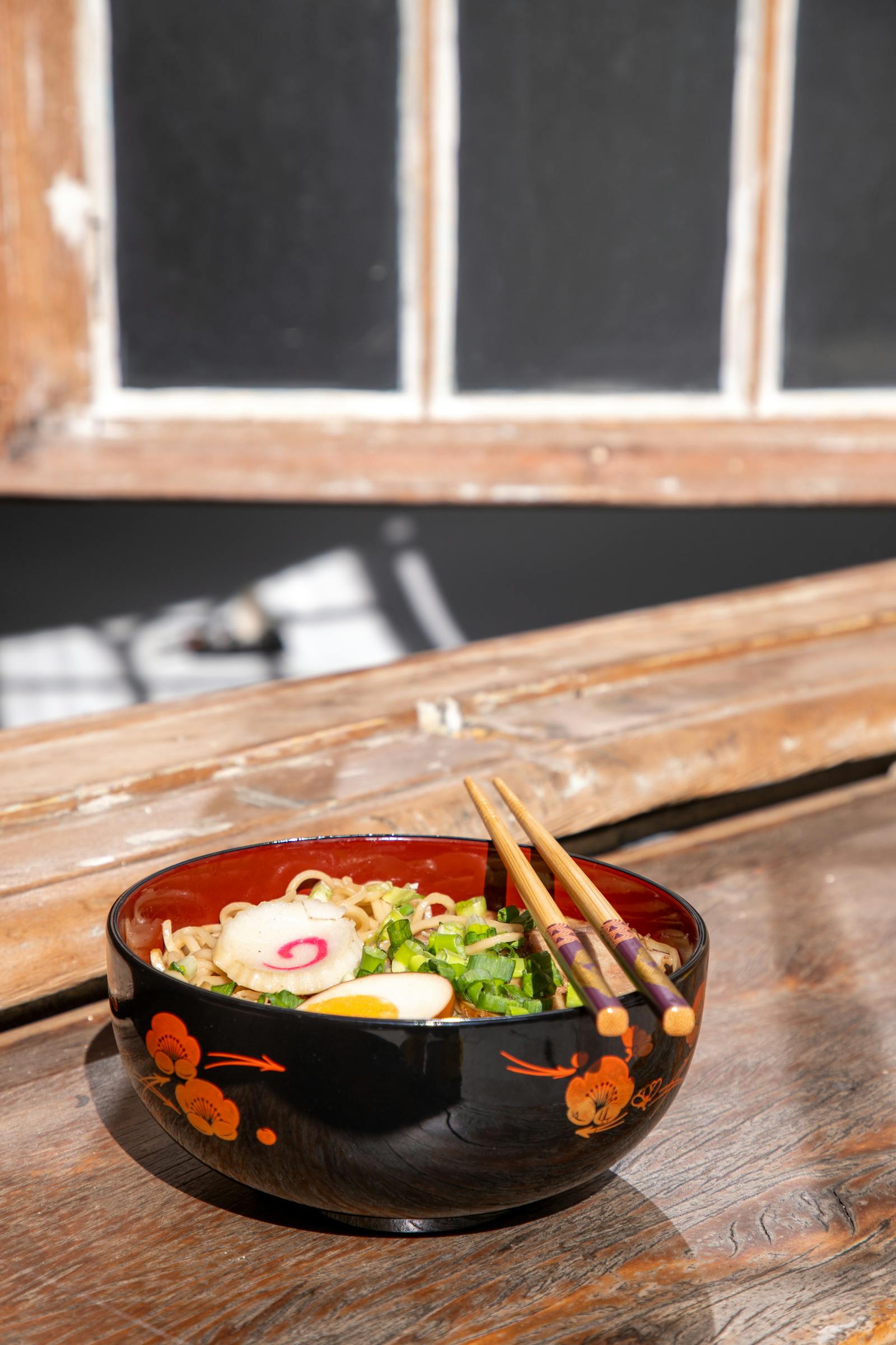 Ramen shoyu en bol noir, baguettes posées